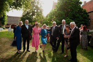 Wedding guests gather outdoors for group photos during sunset celebrations.