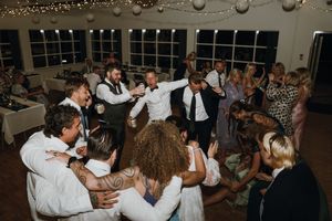 Wedding reception dance floor filled with guests under string lights.