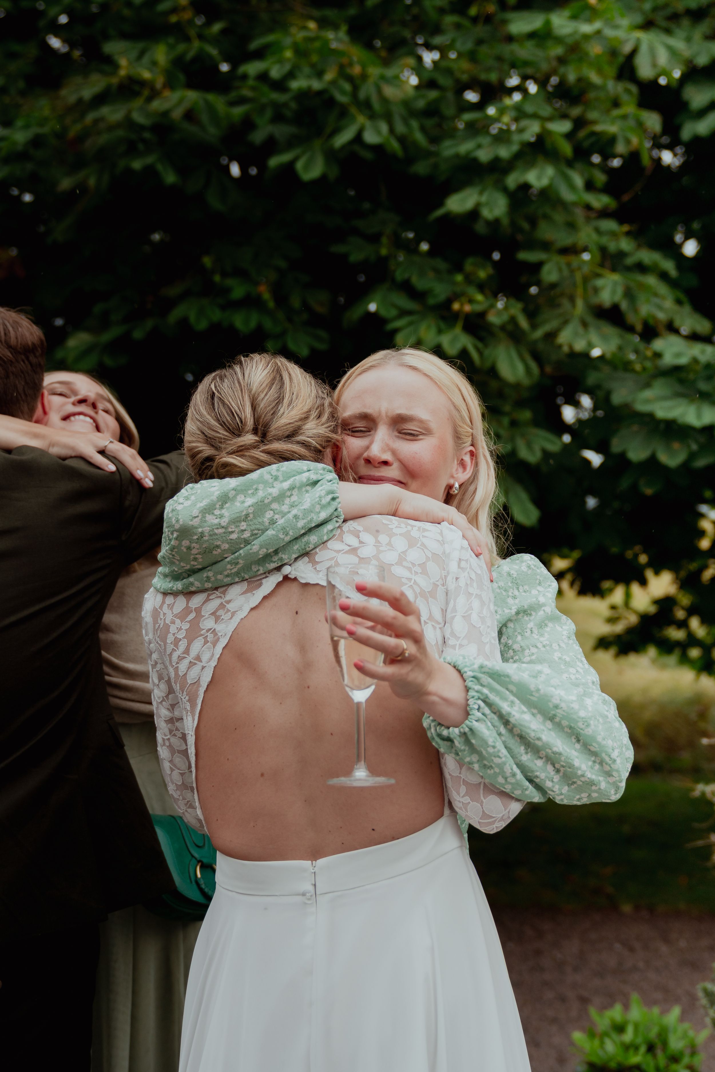 Wedding guests embrace and celebrate during an outdoor garden reception.