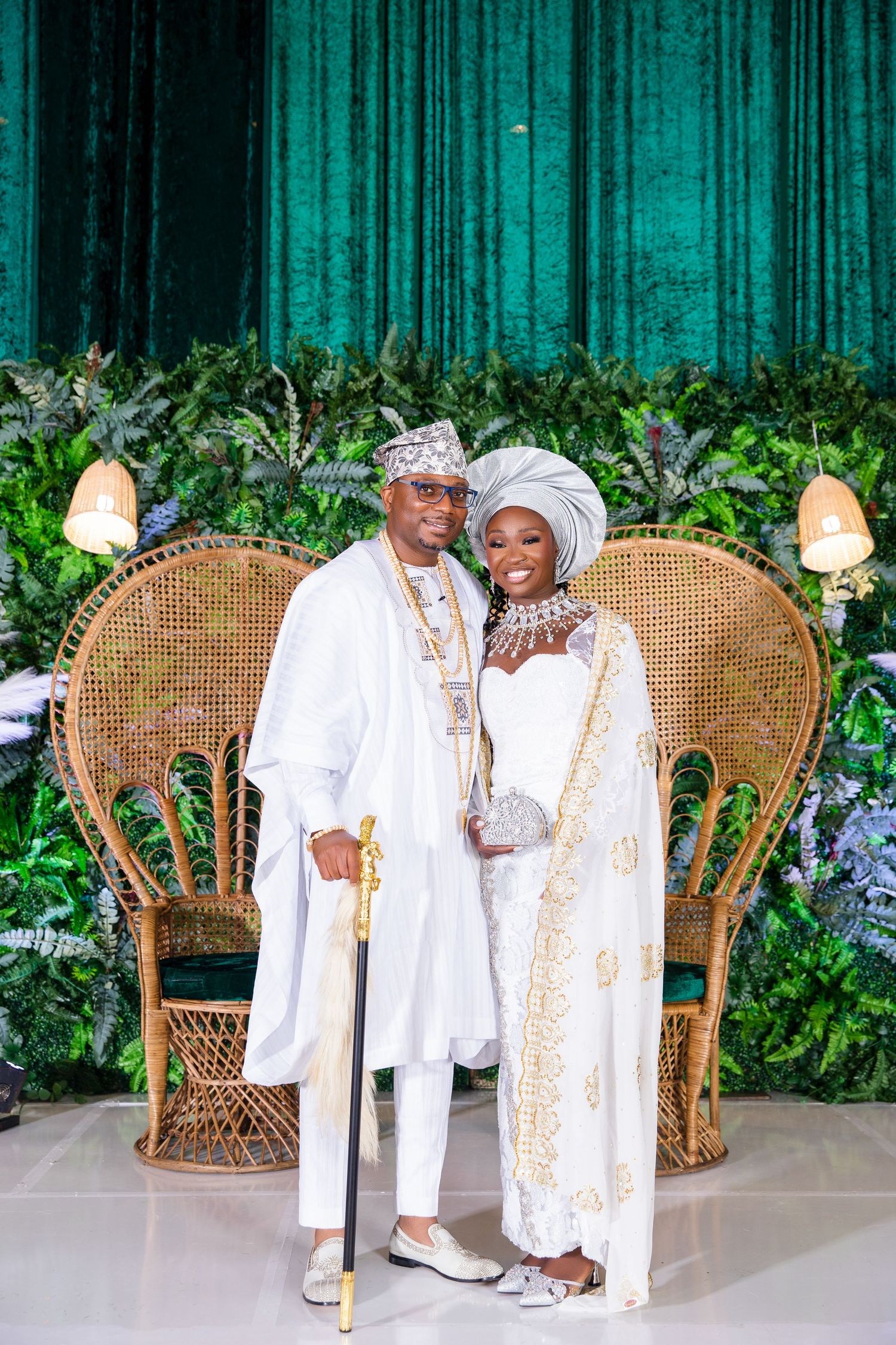 A series of four photos showing a couple in traditional African wedding attire posing on wicker peacock chairs with floral decor.