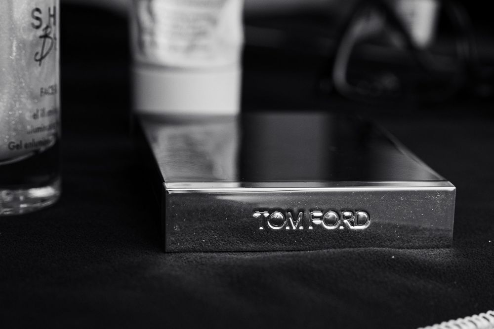 Close-up black and white photo of Tom Ford branding on a dark surface.