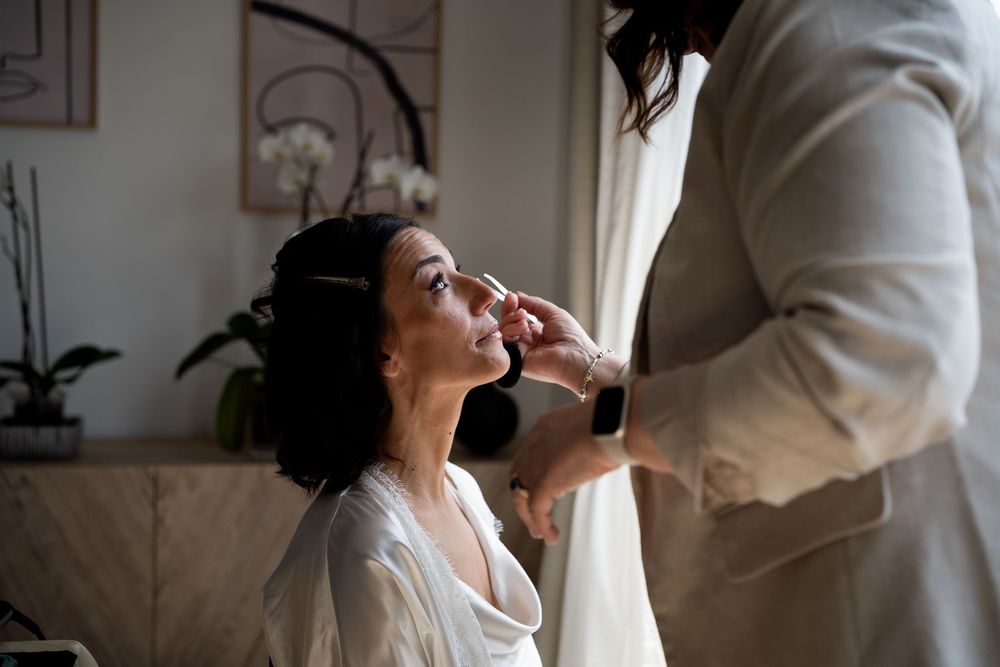 A person getting professional makeup applied during wedding preparations in an elegant interior.