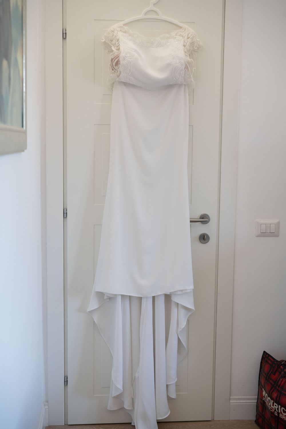 White wedding dress hanging on display against light colored door.
