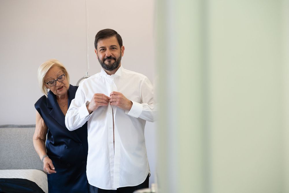 Two people share a lighthearted moment while getting ready in a bright room.