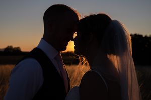Wedding couple silhouettes at sunset create romantic atmosphere during outdoor photo session at golden hour.