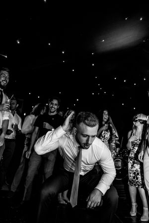 Black and white image shows people dancing and moving in a dim nightclub setting.