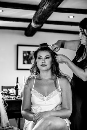 Black and white images show a bride preparing for her wedding with final hair and makeup touches.