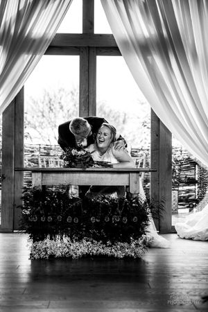 A black and white panoramic photo showing an elegant wedding reception venue with flowing white curtains and decor.