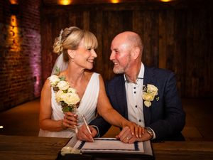 Romantic couple shares playful moments and laughter during their wedding reception in a rustic barn venue.