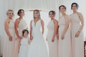 A row of bridesmaids in light pink dresses stand together during a wedding celebration.