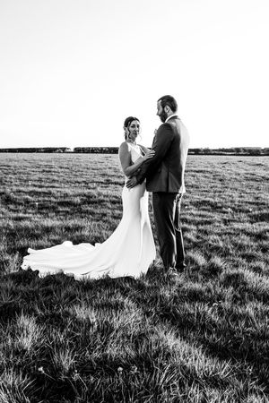 Black and white wedding portraits in a sweeping meadow with dramatic dress movement.