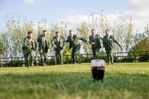 Wedding party members posing in a line against a scenic natural backdrop with tall grass.