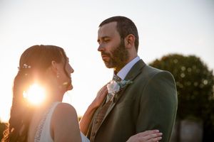 Couple embracing during golden hour sunset in an outdoor wedding setting.