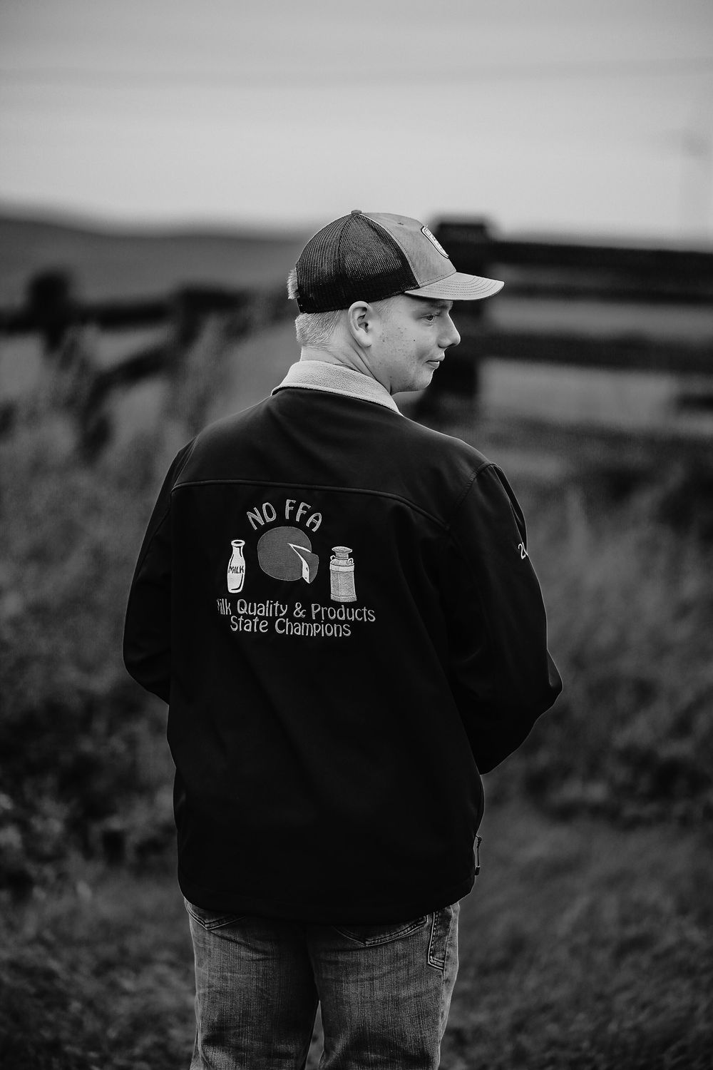 Black and white photos showing the back view of someone wearing a dark jacket with text on a rural field.