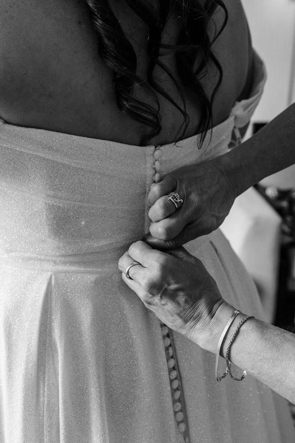 Close-up view of hands adjusting a white dress sash or belt in black and white.