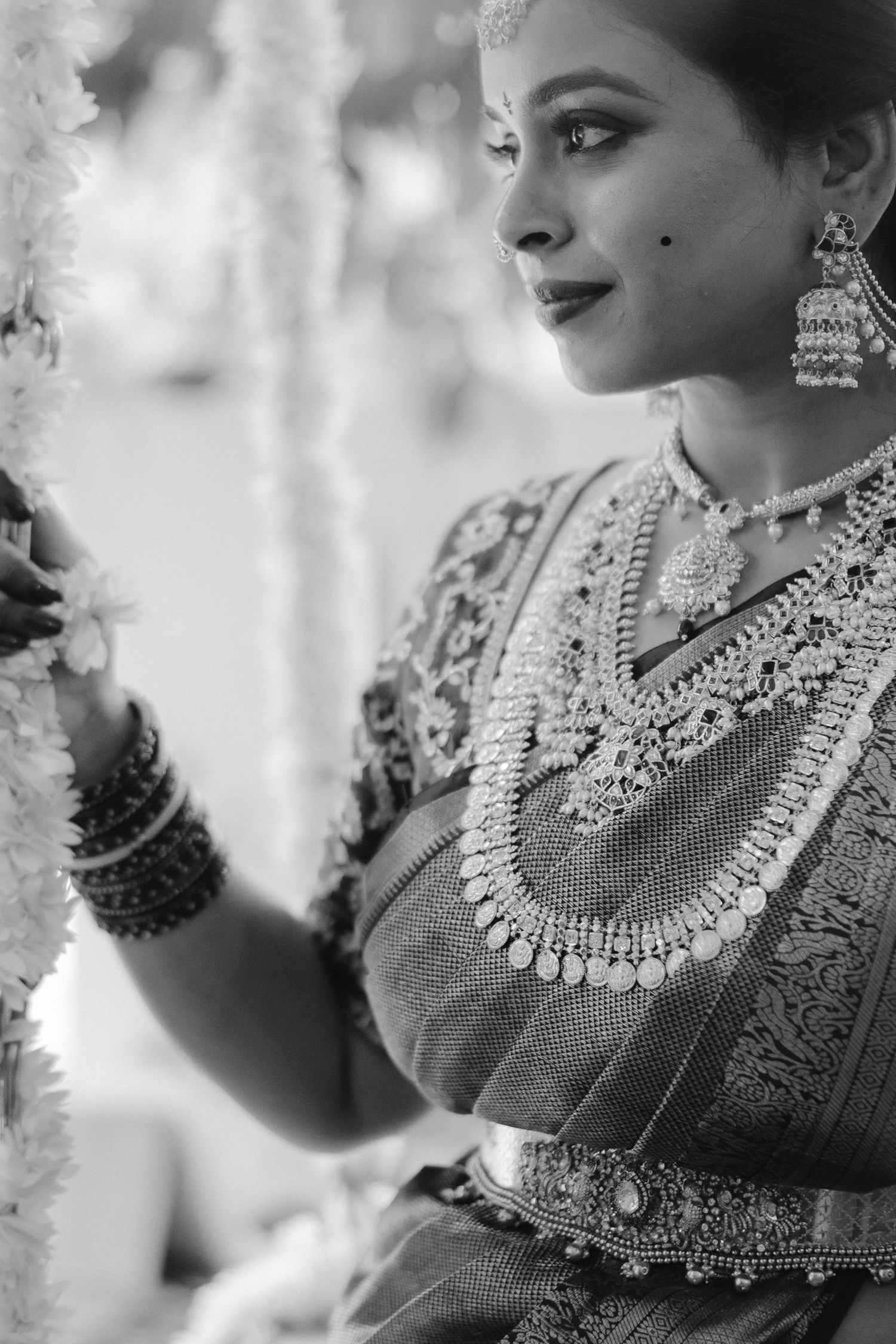 Close-up black and white portrait showcasing intricate Indian bridal jewelry and traditional wedding attire.
