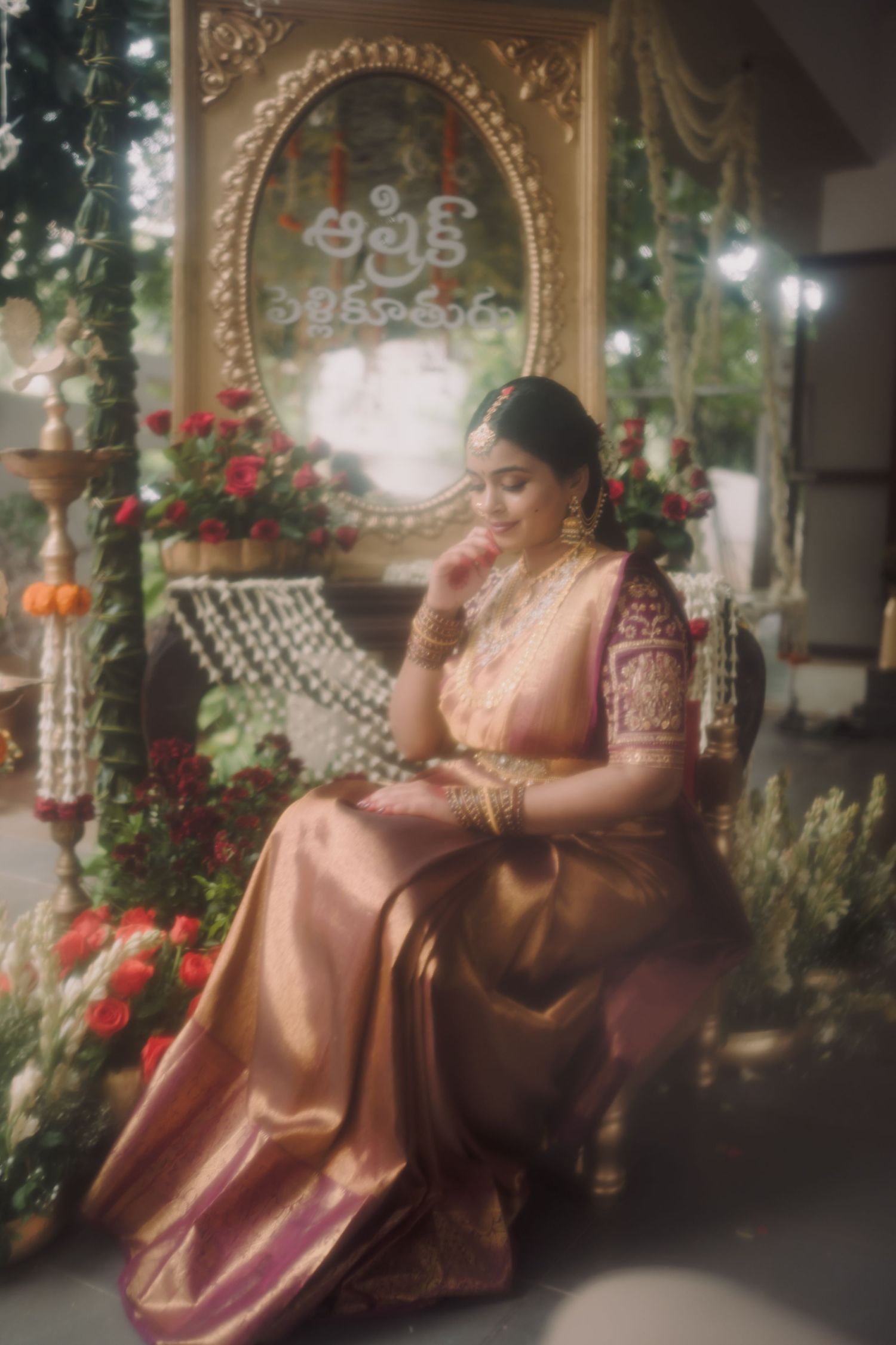 Woman in traditional Indian attire reclining on ornate bench surrounded by flowers and decorative archways.