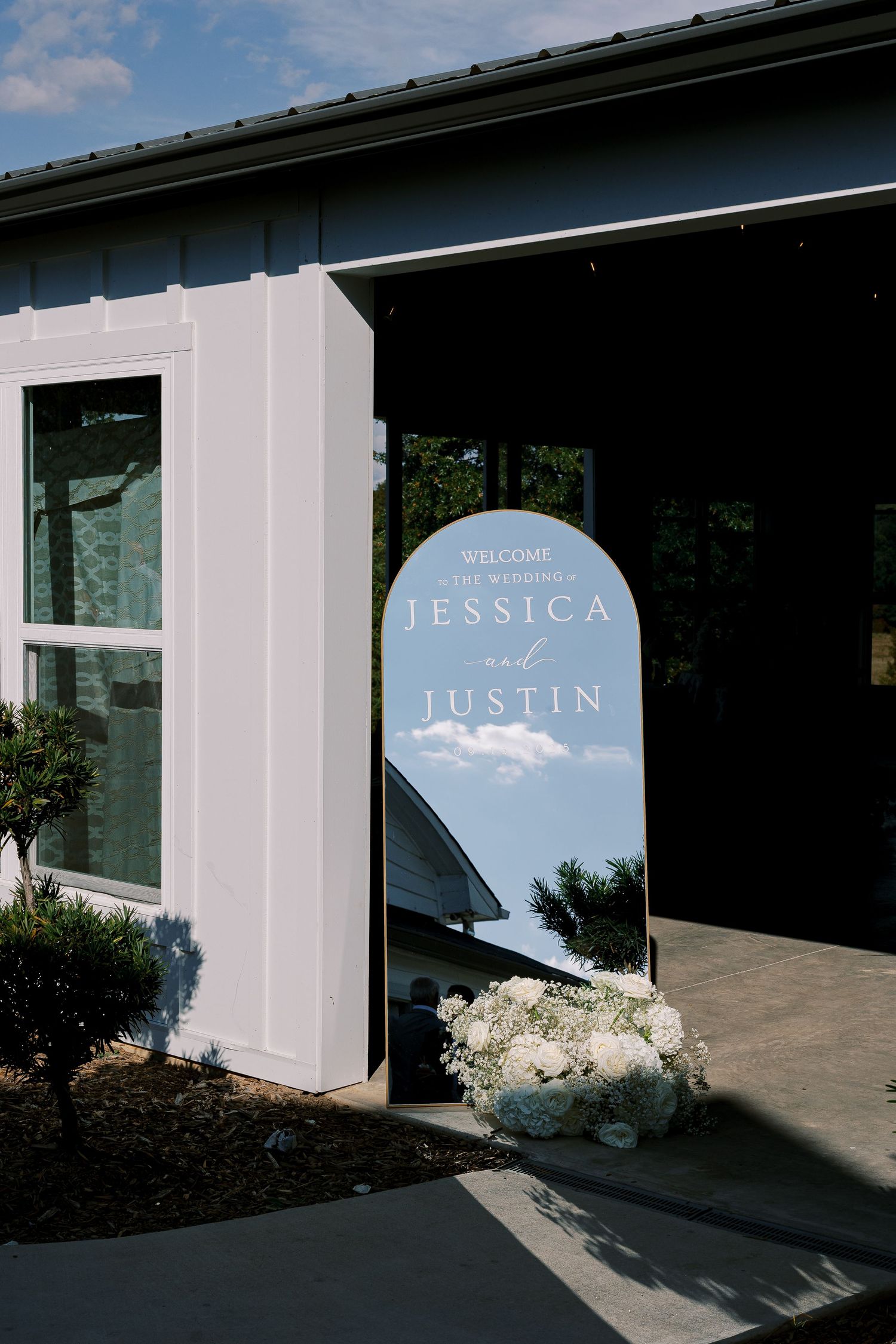 Modern white building exterior with arched blue signage and minimalist design details.