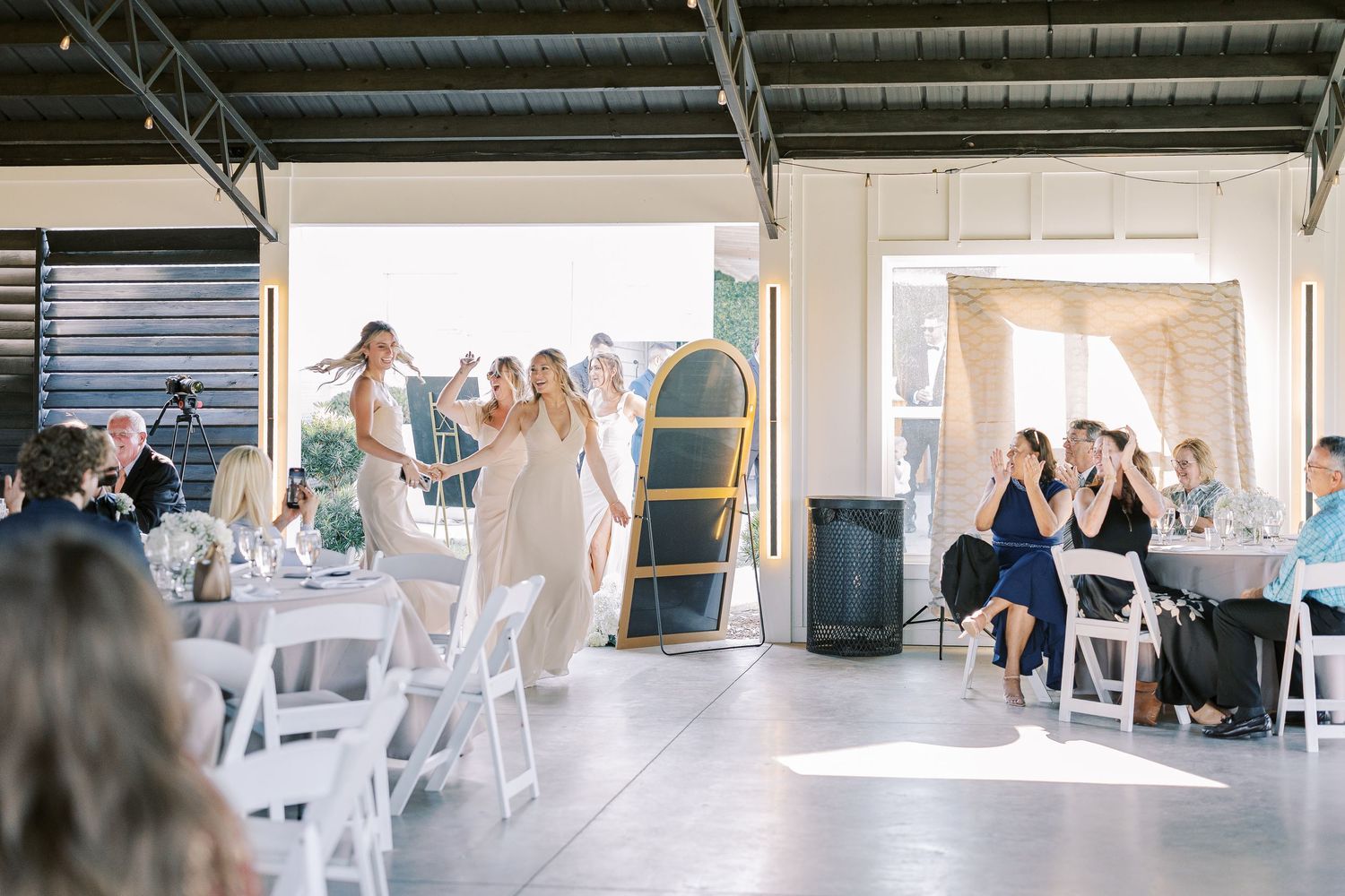 Panoramic view of a modern industrial warehouse space set up with white chairs and tables for an indoor event gathering.