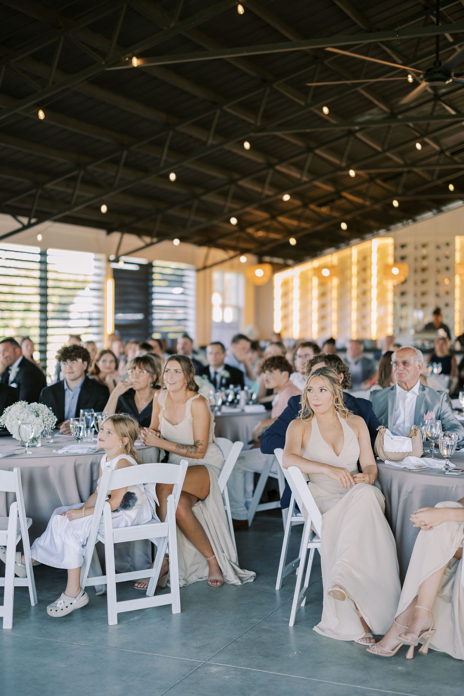 Wedding reception venue decorated with string lights and white chairs for guests during a special celebration.