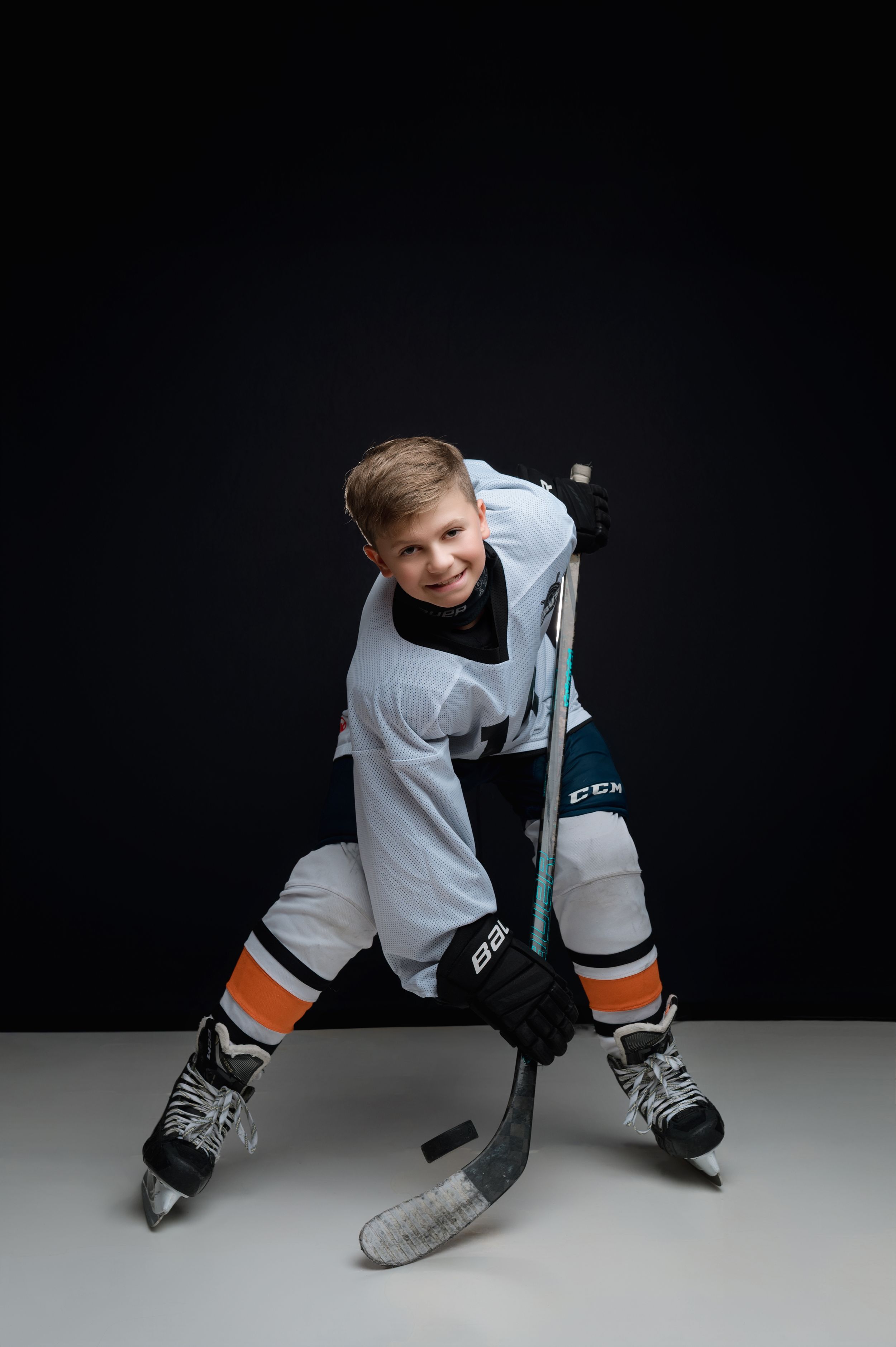 A young hockey player in white jersey demonstrates proper puck handling technique in a sequence of shots.