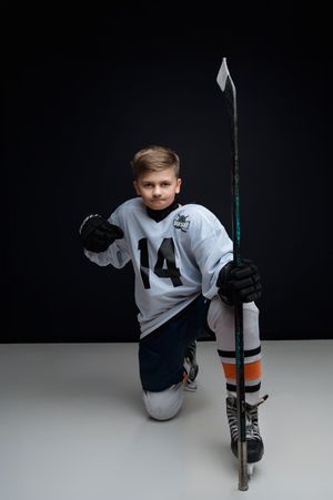 A hockey player in white jersey performs sliding poses on roller skates against a dark studio background.
