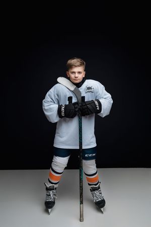 Hockey player in white jersey and protective gear holds stick in defensive stance from four different angles on dark background.