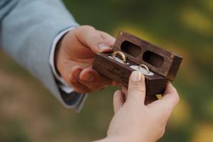 Person loading bullets into a rifle magazine clip during target practice outdoors.