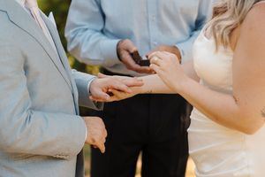 Closeup of hands during a wedding ceremony with rings being exchanged outdoors.