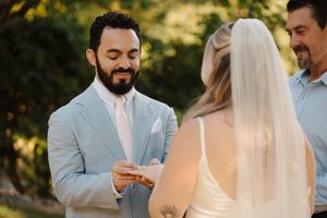 A groom reads his wedding vows during an outdoor ceremony in warm natural lighting at golden hour.