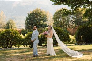 A couple walks together in an outdoor scenic setting during sunset while the bride's veil flows in the breeze.