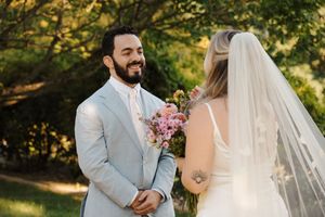 A bride and groom share joyful moments during their outdoor garden wedding ceremony in natural sunlight.