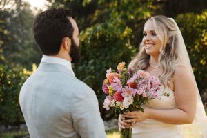 A joyful outdoor wedding moment between a bride and groom captured in backlit golden sunlight.