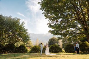 Outdoor wedding ceremony in a scenic mountain setting with tall trees framing the scenic vista on a sunny day.