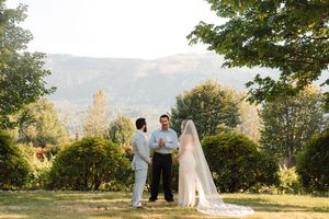 A picturesque outdoor wedding ceremony setup against a backdrop of rolling hills and trees in golden sunlight.