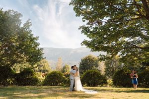 Wedding party enjoying outdoor celebration under autumn trees during golden hour sunset.