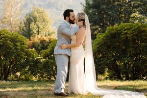 A couple shares a romantic embrace in a sunlit garden setting during their wedding photoshoot.