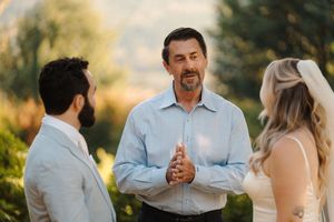 Wedding party stands together on a sunny day in an outdoor garden setting for a celebration ceremony.