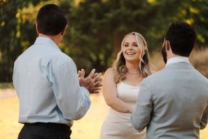 A couple holds hands and dances outdoors at sunset during their wedding celebration.