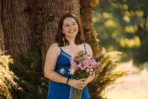 Wedding party wearing blue and white dresses holding floral bouquets in a sunny outdoor setting.