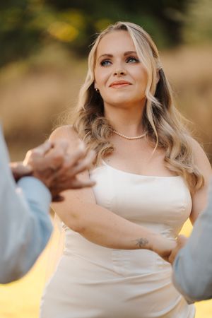 Intimate wedding ceremony scene with couple exchanging vows in golden afternoon sunlight.