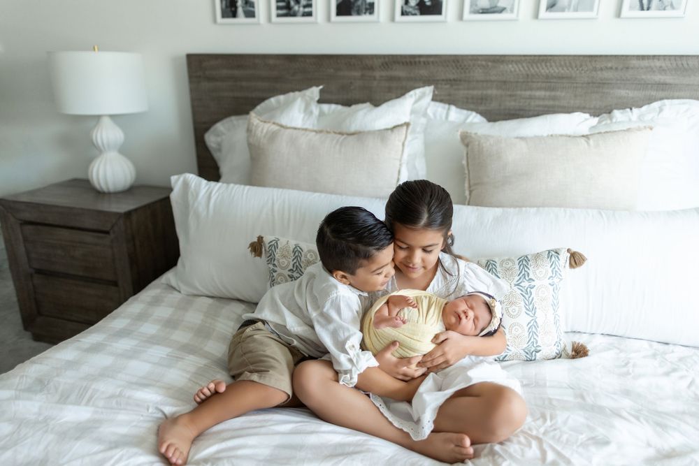 Collection of black and white photos showing tender parenting moments of a person holding a small baby in bed.