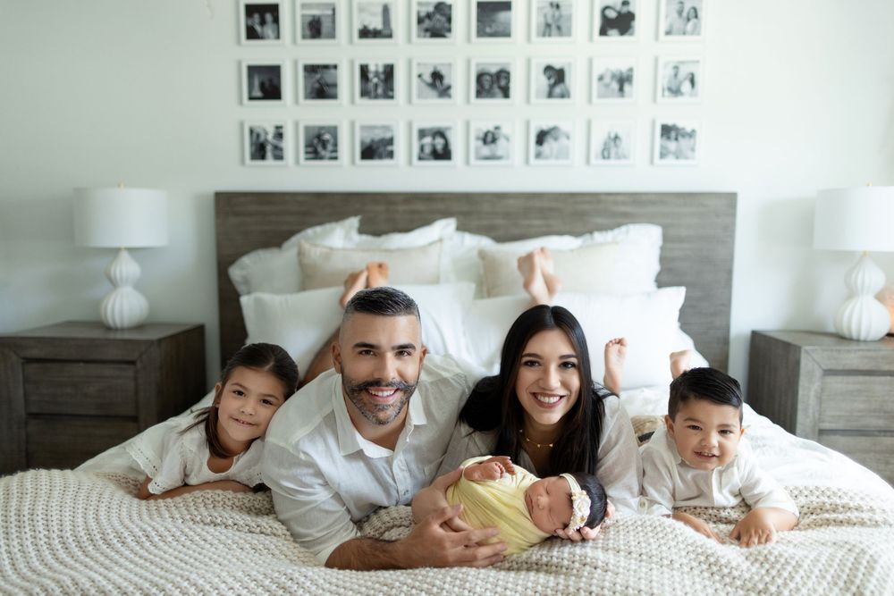 Happy family lying together in comfortable white bed enjoying relaxed weekend morning at home.