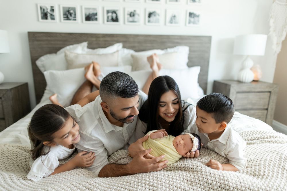 Happy family lounging together on white bedding while sharing tender moments of affection.