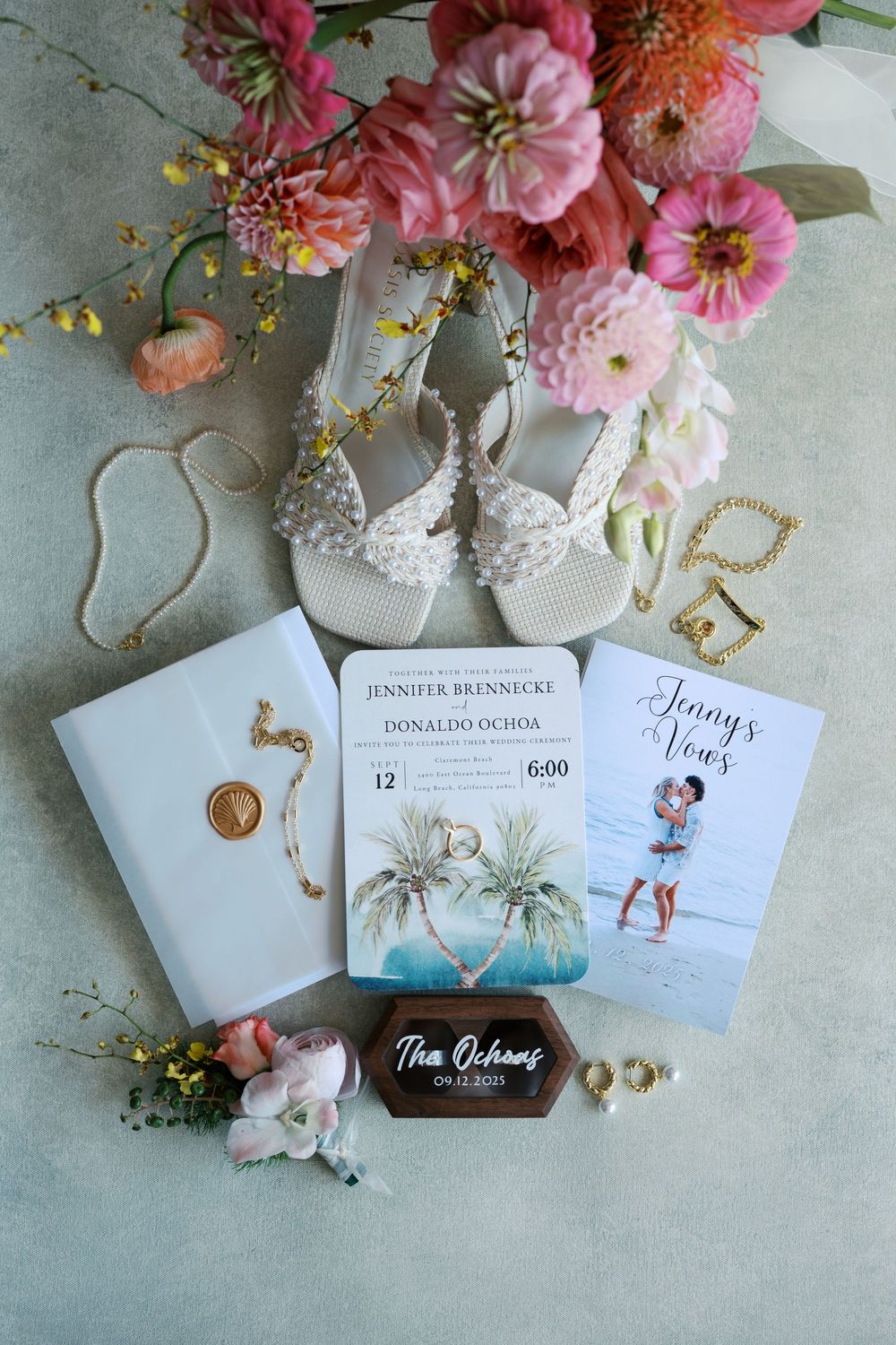 Wedding invitation suite with pink florals, decorative cards and delicate details on a light gray surface.