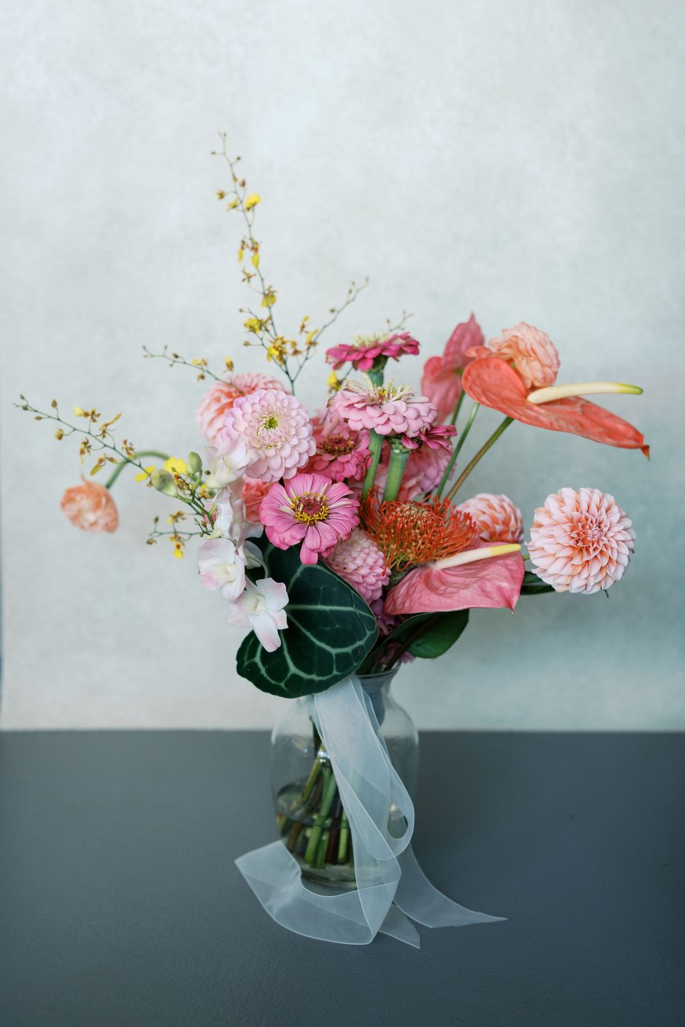 Four elegant floral arrangements featuring pink and coral blooms with delicate greenery against a grey background.