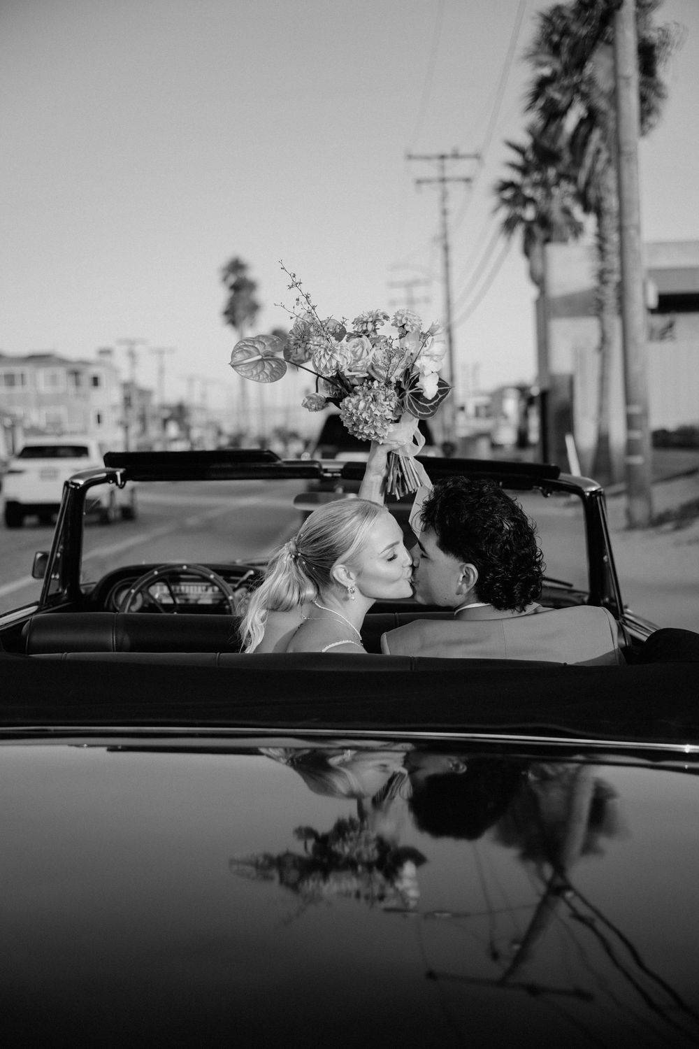 Classic black and white portrait of newlyweds in vintage convertible car.