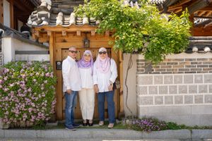 Tourists exploring flowering gardens and traditional architecture in Korean hanok village.