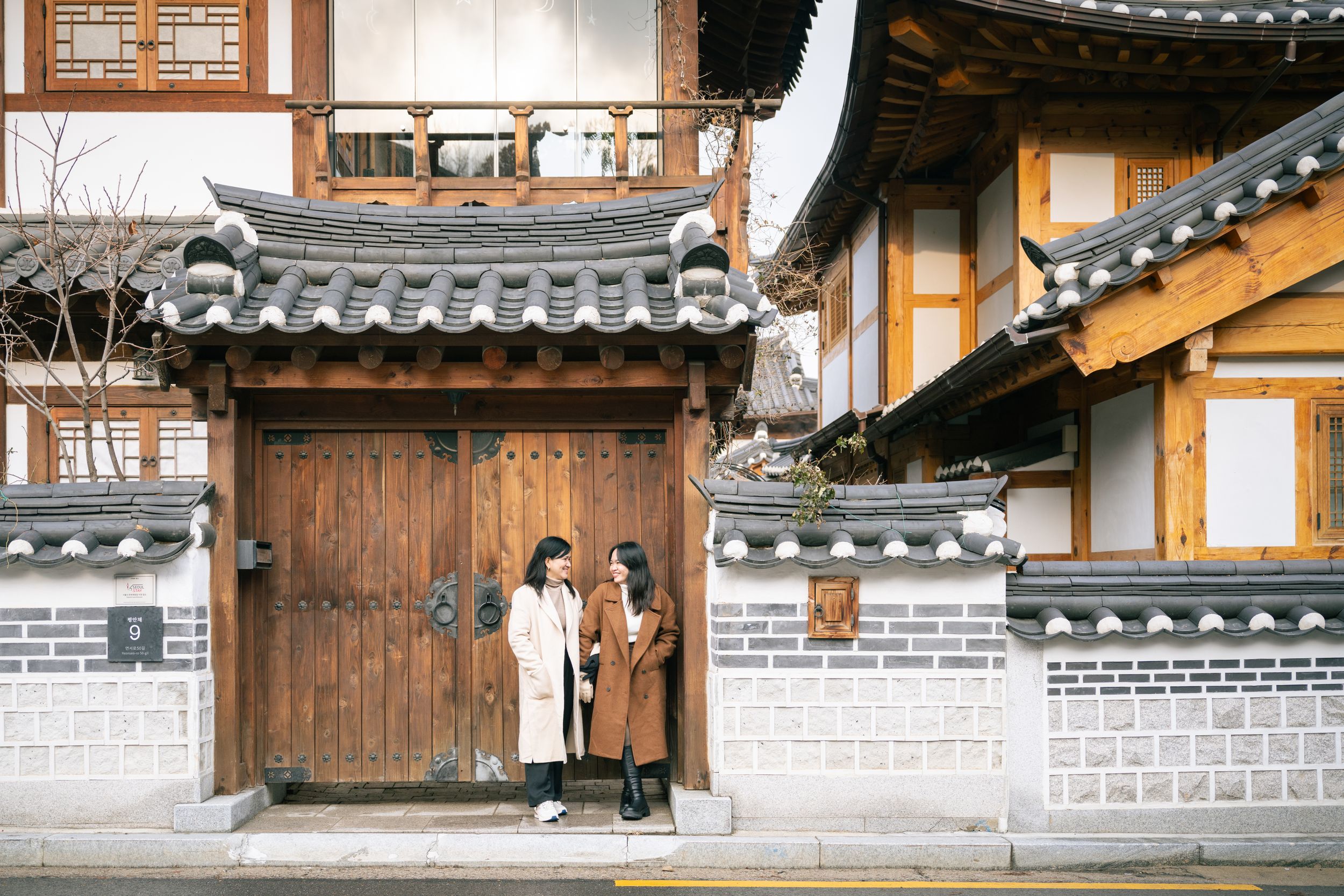 Row of traditional Korean hanok buildings with white walls and dark wooden beams under tile roofs.