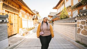 Traditional Korean hanok buildings line a narrow stone pathway with ornate tile roofs and wooden architecture.